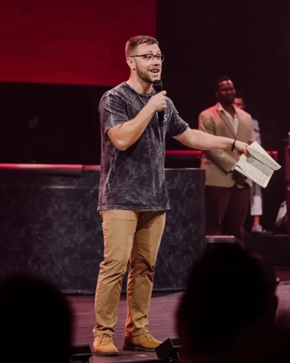 Zach on stage with a microphone, speaking to a crowd
